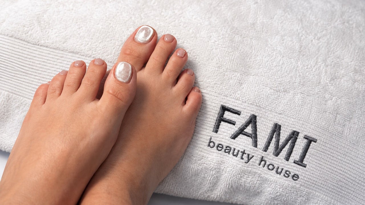 Voeten met parelmoer gellak op een witte handdoek met het borduursel FAMI beauty house