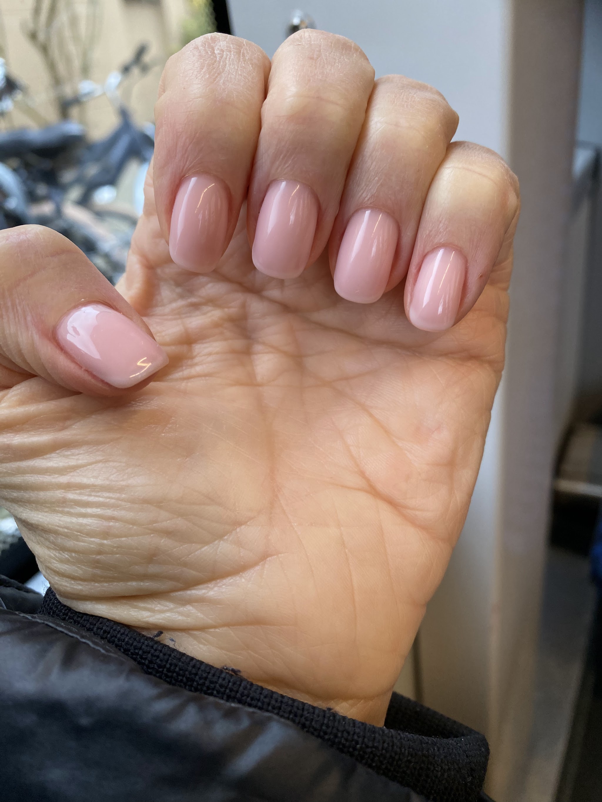 Zachtroze glanzende nagels, close-up van een hand